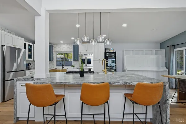 a kitchen with stainless steel appliances granite countertop a table chairs and a refrigerator