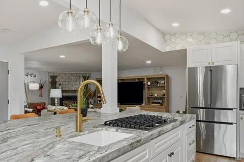 a kitchen with stainless steel appliances granite countertop a refrigerator a sink and a stove
