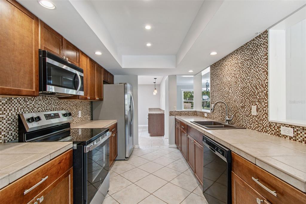 1470 Burnham Lane Dunedin, FL 34698 - Photo 13 of 42 a kitchen with stainless steel appliances granite countertop a sink stove microwave and cabinets