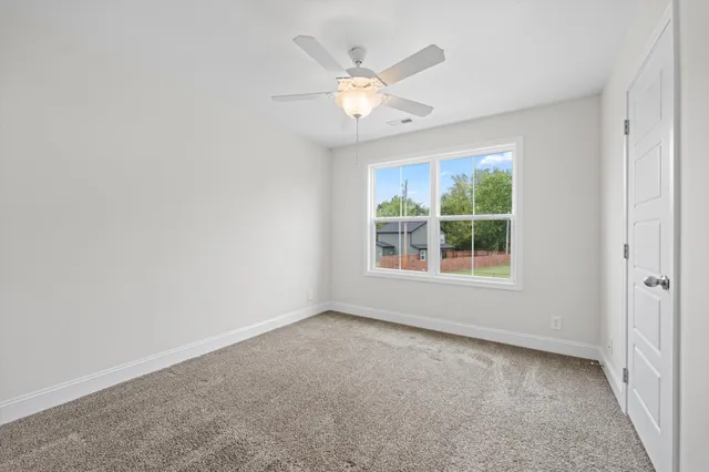 an empty room with window and ceiling fan