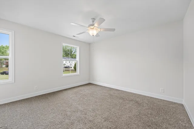 an empty room with windows and fan