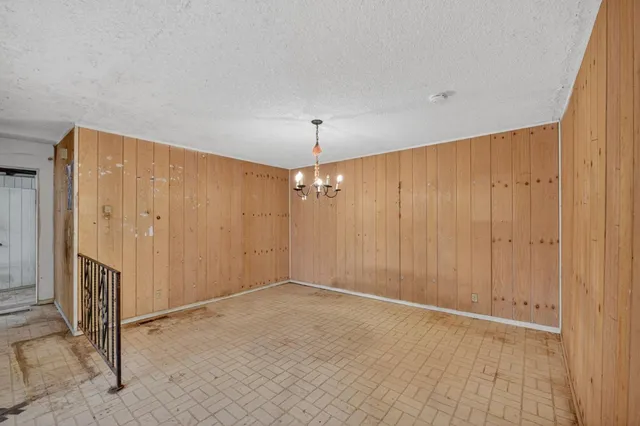 an empty room with chandelier fan and hallway view