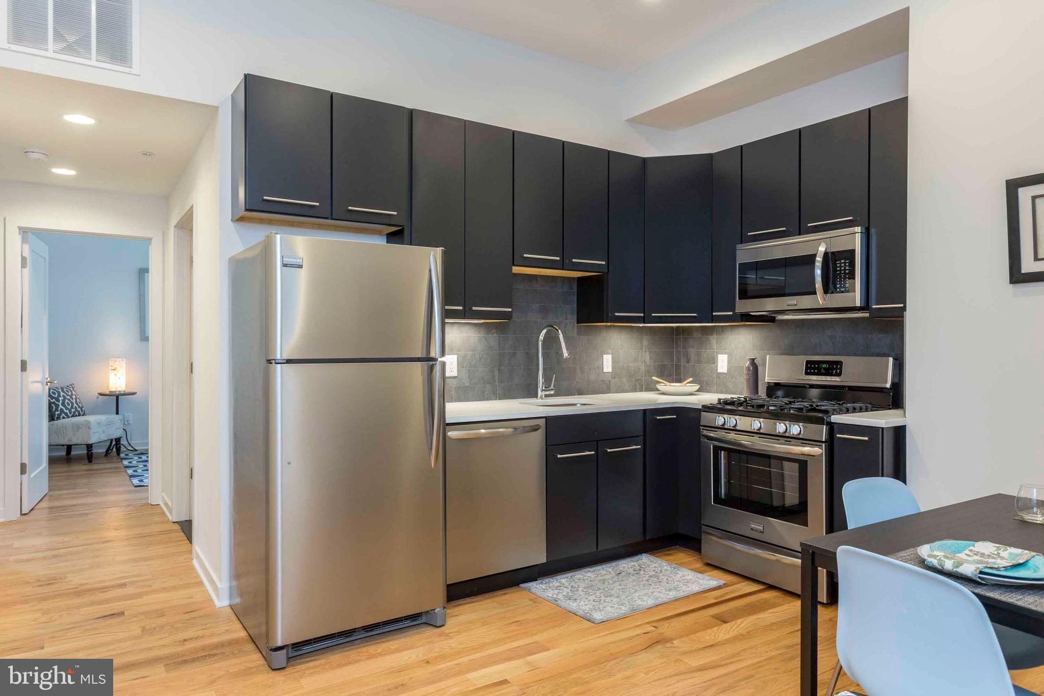 2028-34 Rittenhouse Square, Unit 102 Philadelphia, PA 19103 - Photo 2 of 13 a kitchen with stainless steel appliances granite countertop a refrigerator stove a sink dishwasher and microwave oven