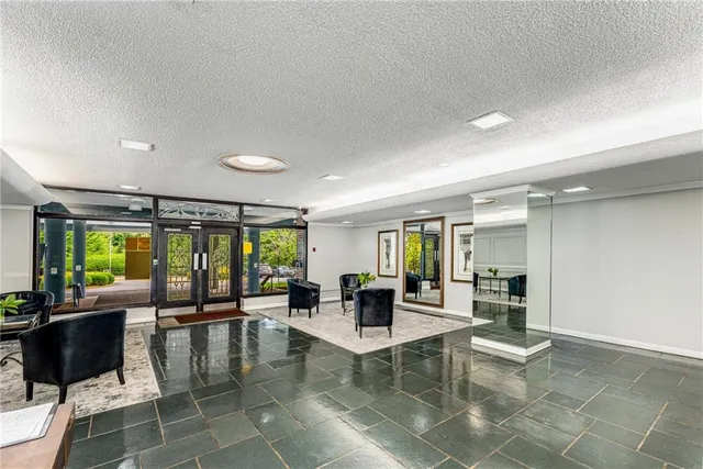 a dining hall with couches a coffee table and chairs with a large window