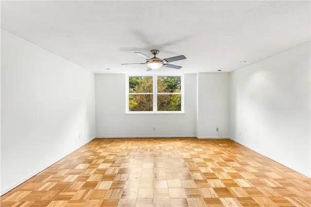 an empty room with windows and ceiling fan