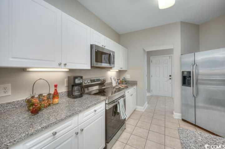 70 Addison Cottage Way, Unit 319 Murrells Inlet, SC 29576 - Photo 5 of 30 Kitchen featuring stainless steel appliances, light stone counters, white cabinetry, and light tile patterned flooring