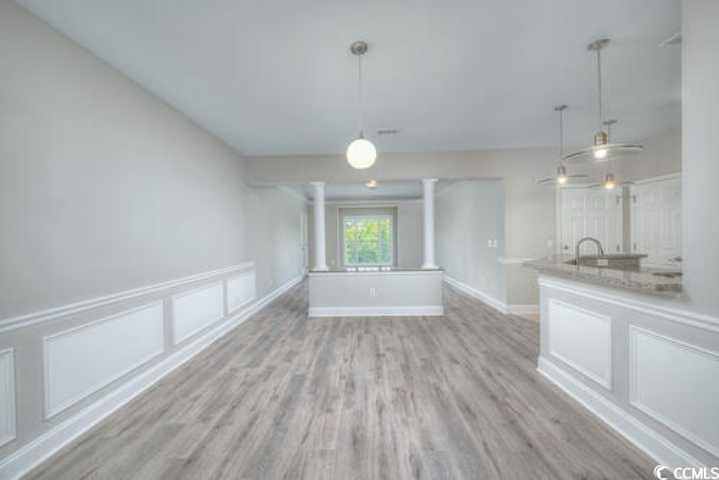 70 Addison Cottage Way, Unit 319 Murrells Inlet, SC 29576 - Photo 7 of 30 Unfurnished dining area with a decorative wall, light wood-type flooring, and a wainscoted wall