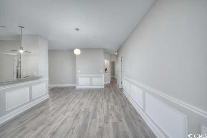 70 Addison Cottage Way, Unit 319 Murrells Inlet, SC 29576 - Photo 8 of 30 Unfurnished living room with a decorative wall, light wood-style floors, and a wainscoted wall