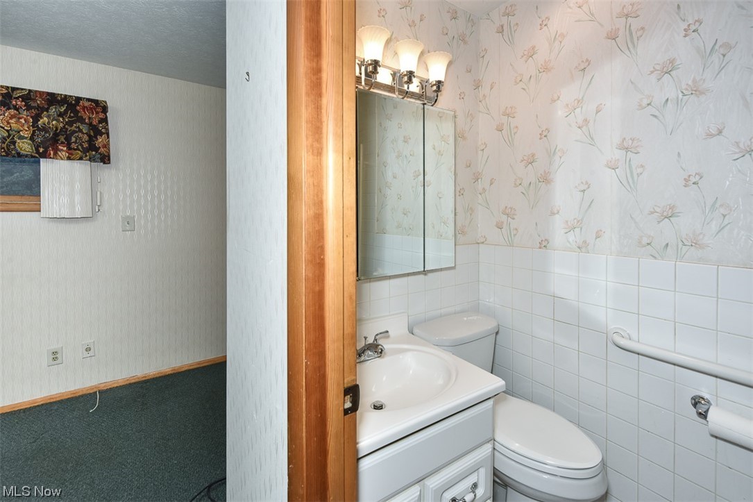 4026 Stonehaven Road Cleveland, OH 44121 - Photo 18 of 30 Bathroom with toilet, tile walls, a textured ceiling, and vanity with extensive cabinet space