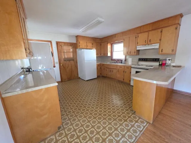 a kitchen with a sink a stove top oven a refrigerator cabinets and a dining table