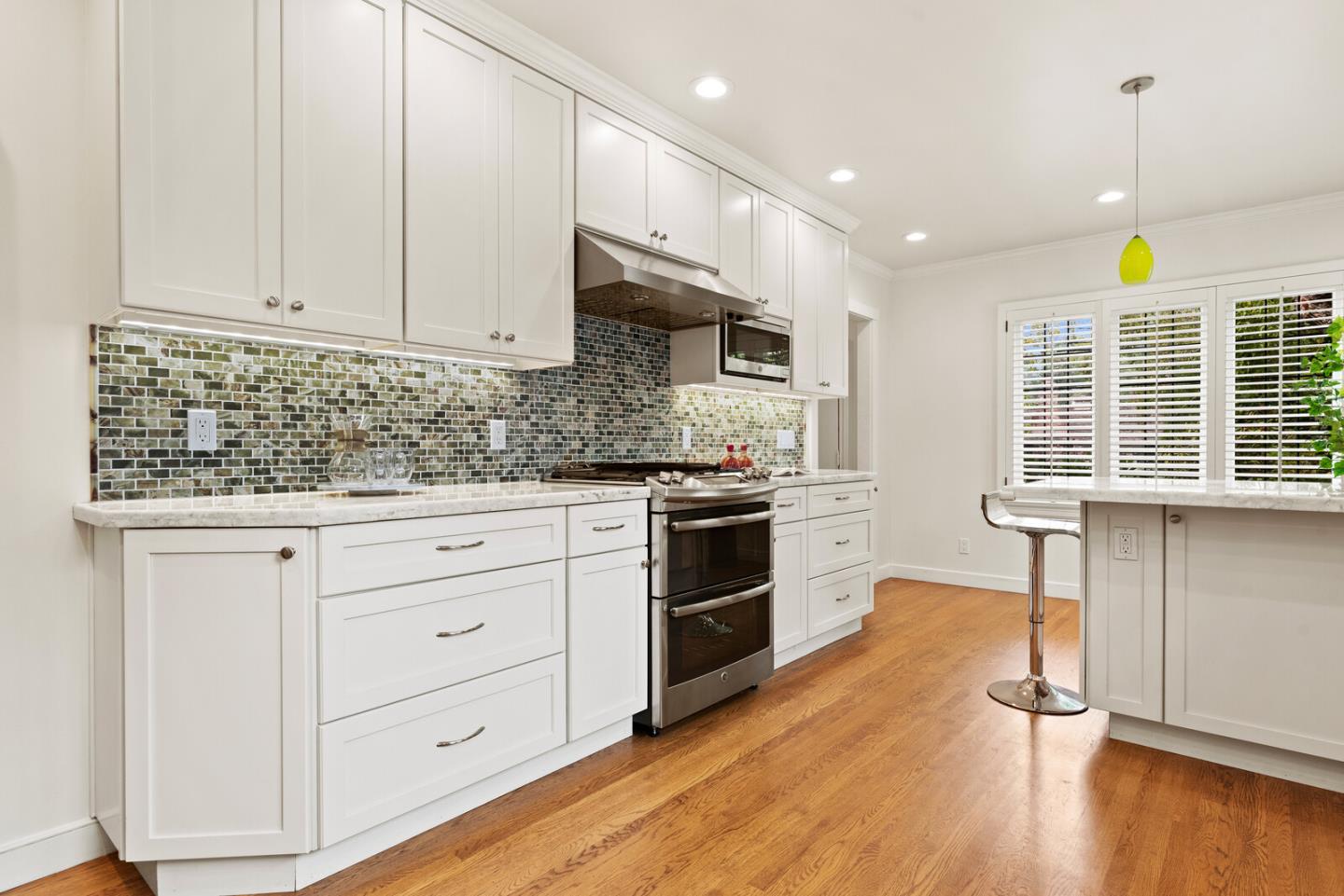 750 Edgewood Road San Mateo, CA 94402 - Photo 12 of 26 a kitchen with granite countertop a stove a sink and white cabinets with wooden floor