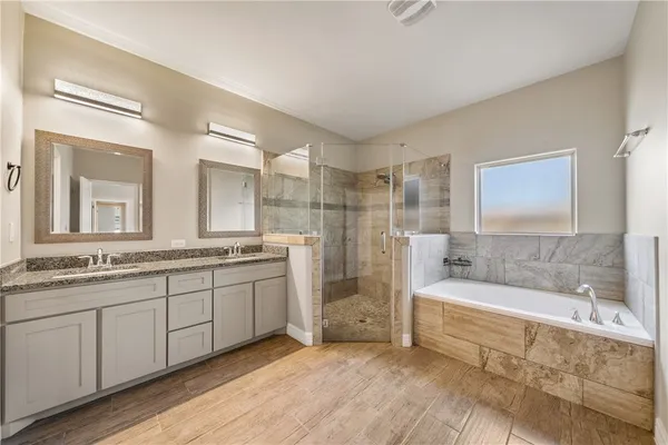 a bathroom with a tub a double vanity sink and a mirror