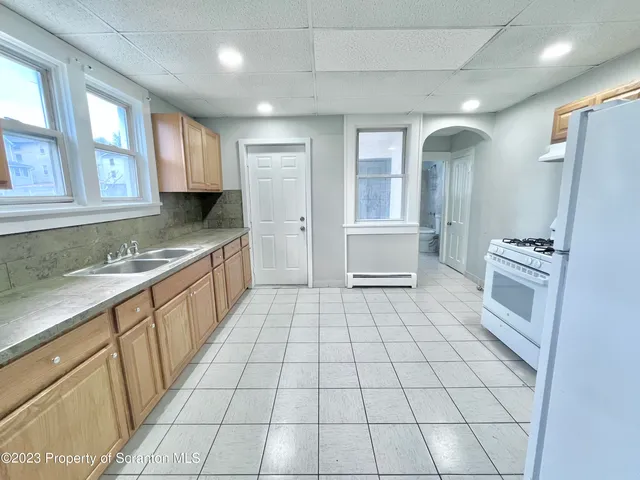 a large white kitchen with granite countertop a sink a stove a washer and dryer