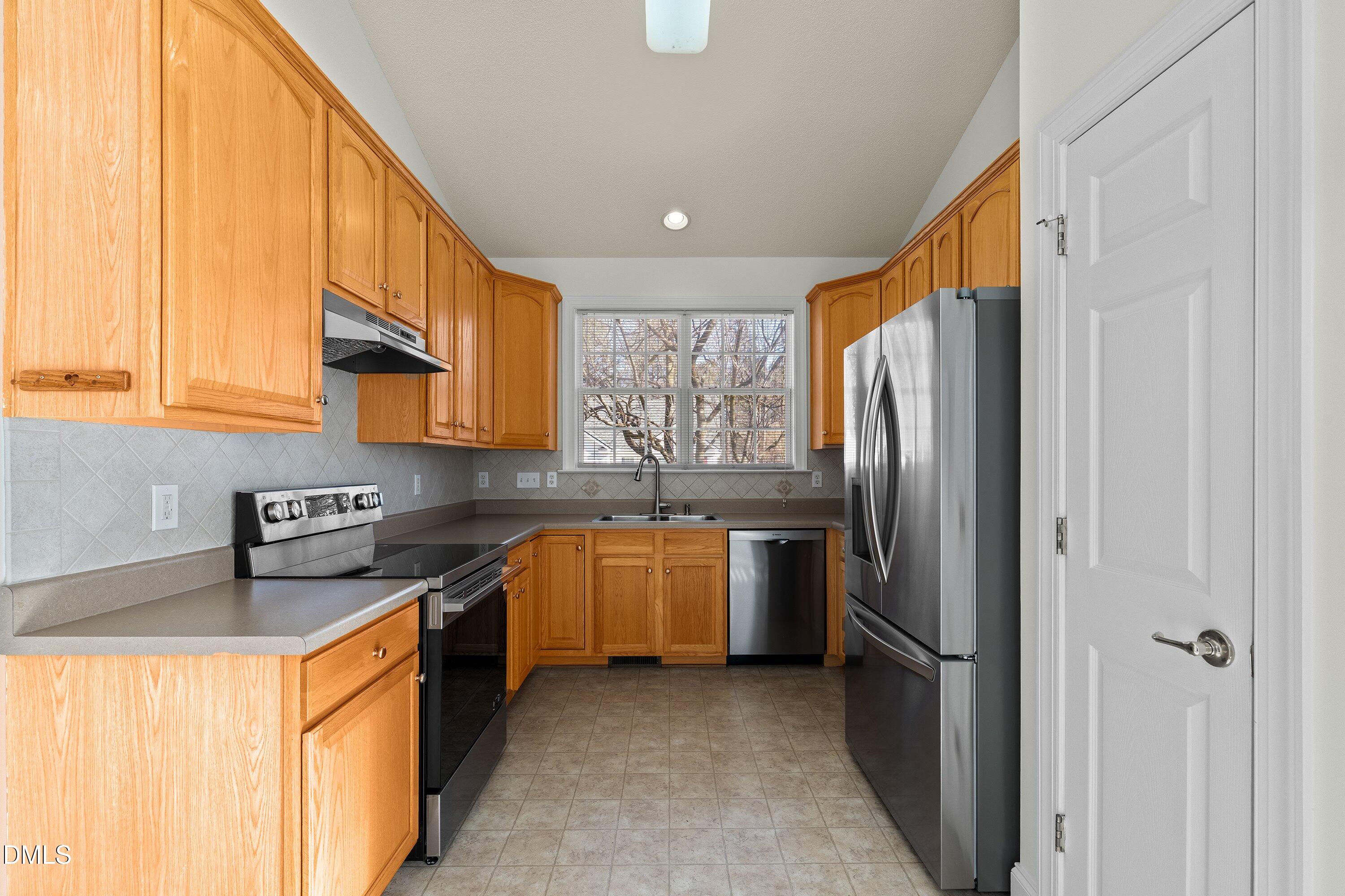 105 Rockport Ridge Way Cary, NC 27519 - Photo 5 of 43 a kitchen with stainless steel appliances granite countertop a refrigerator a sink dishwasher a oven with white cabinets and wooden floor