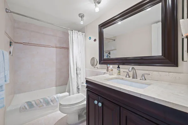 a bathroom with a sink a toilet a mirror and shower