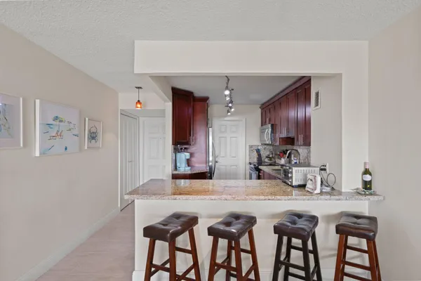 a kitchen with kitchen island granite countertop a dining table chairs cabinets and stainless steel appliances