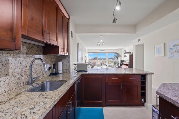 a kitchen with granite countertop stainless steel appliances a sink a stove and cabinets