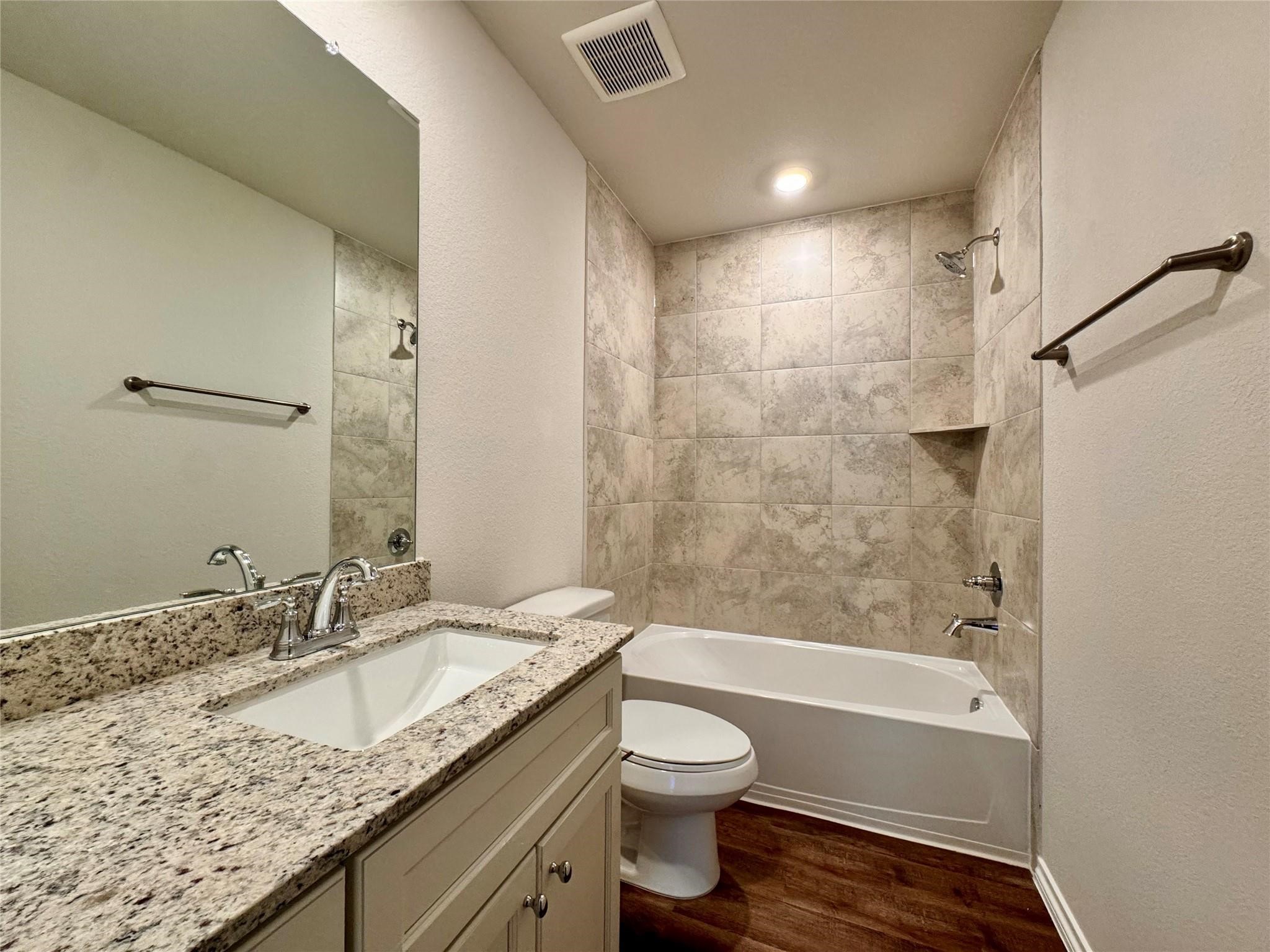 25786 John Wayne Court Splendora, TX 77372 - Photo 10 of 17 a bathroom with a granite countertop sink a toilet and bathtub