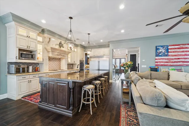 a living room with stainless steel appliances granite countertop furniture wooden floor and a chandelier