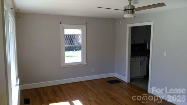 a view of an empty room with wooden floor and a window