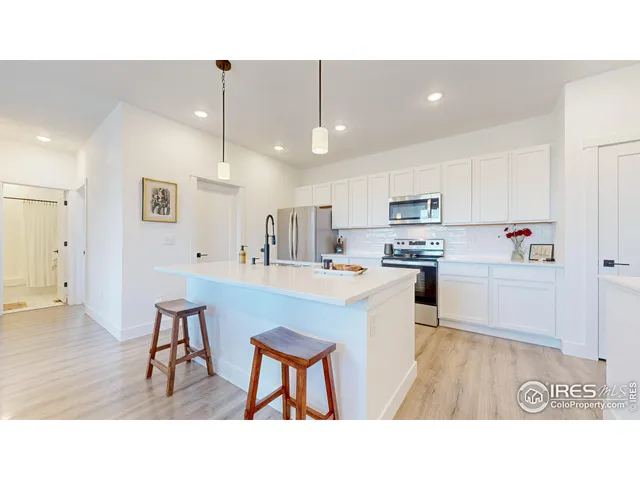 a kitchen with kitchen island a sink stainless steel appliances and white cabinets