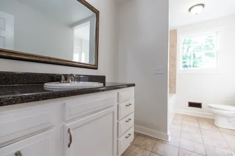 a bathroom with a granite countertop sink a toilet and a mirror