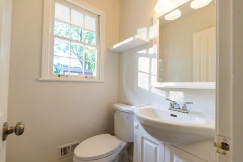 a bathroom with a sink a toilet and a window