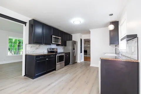 a modern kitchen with stainless steel appliances granite countertop a stove refrigerator and a sink