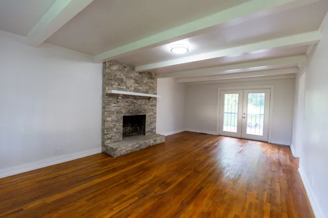a view of an empty room with wooden floor fireplace and a window