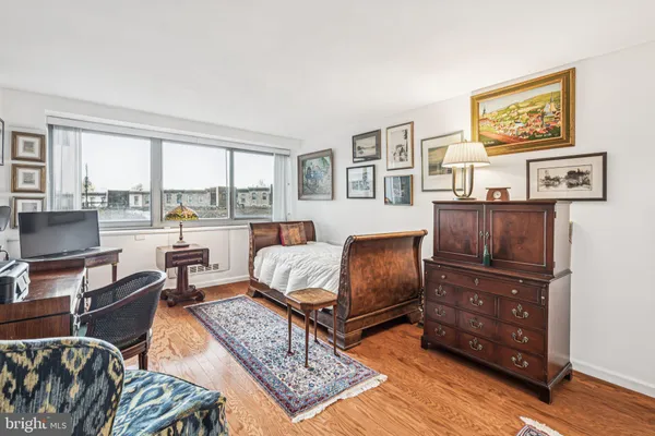 a living room with furniture and a dresser next to a window