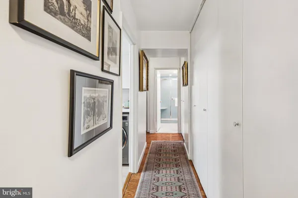 a view of a hallway with wooden floor and a bathroom