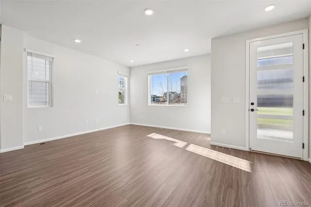 an empty room with wooden floor closet and windows