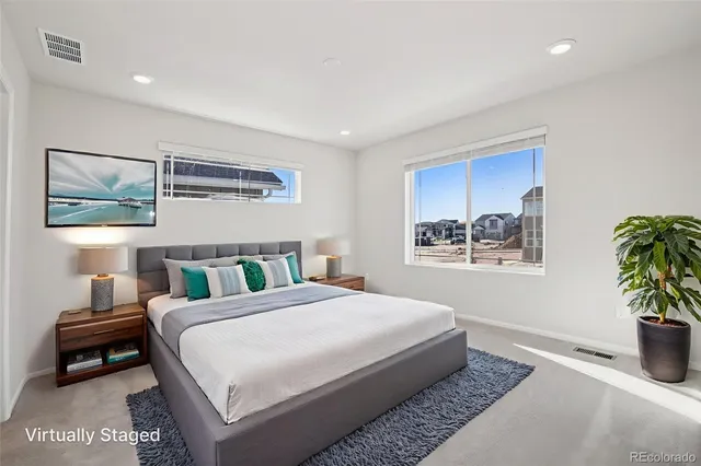 a bedroom with a bed a painting on the wall and a potted plant