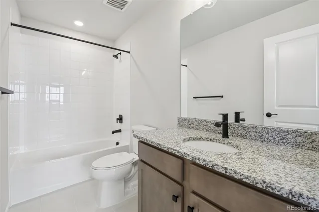 a bathroom with a granite countertop sink a toilet and shower
