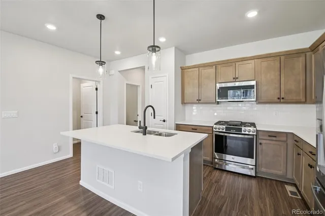 a kitchen with stainless steel appliances granite countertop a sink a stove a refrigerator and island with wooden floor