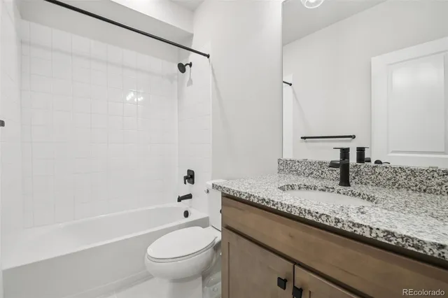 a bathroom with a granite countertop sink a toilet a mirror and bathtub
