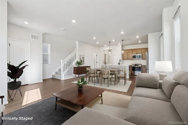 a living room with furniture kitchen view and a wooden floor