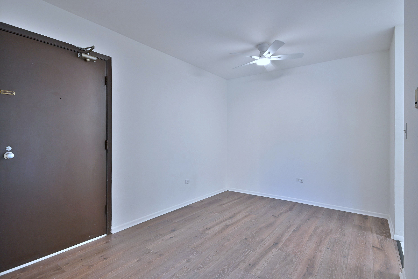 6177 Knoll Wood Road, Unit 102 Willowbrook, IL 60527 - Photo 4 of 19 an empty room with wooden floor and fan