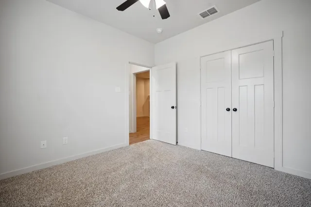 a view of an empty room and chandelier fan