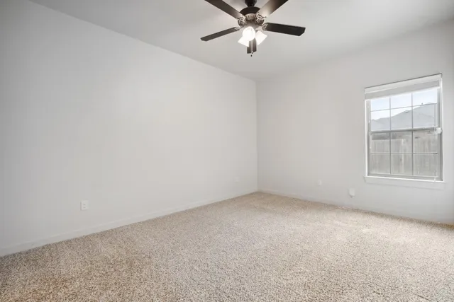 an empty room with a window and a fan