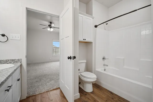 a bathroom with a granite countertop bathtub shower sink vanity and toilet