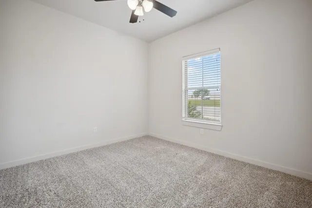 an empty room with a chandelier fan and windows