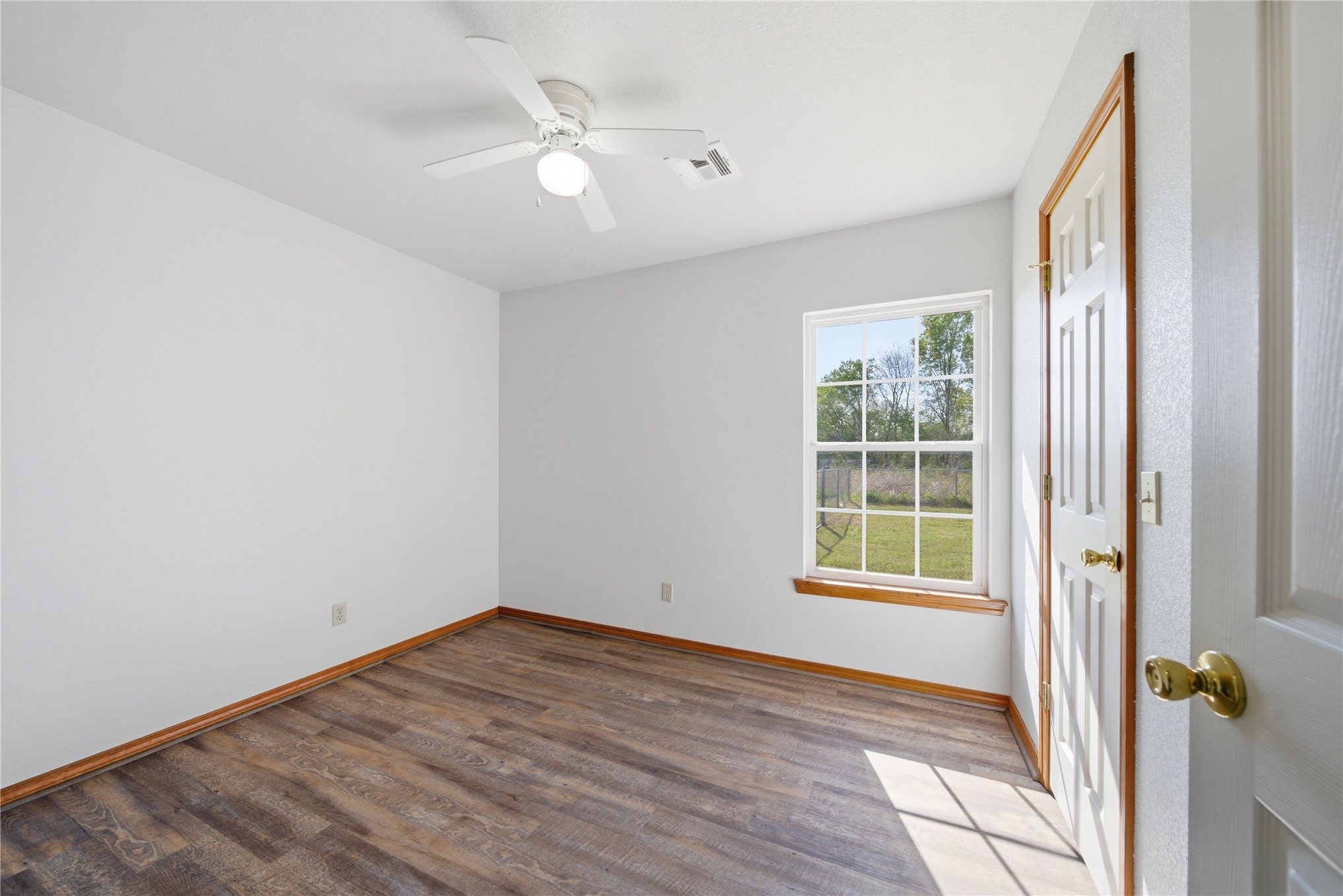 511 Cemetery Road Oktaha, OK 74450 - Photo 19 of 28 Wood-finish flooring with a coordinating baseboard, a ceiling-mounted fan with integrated lighting, and a single-pane window