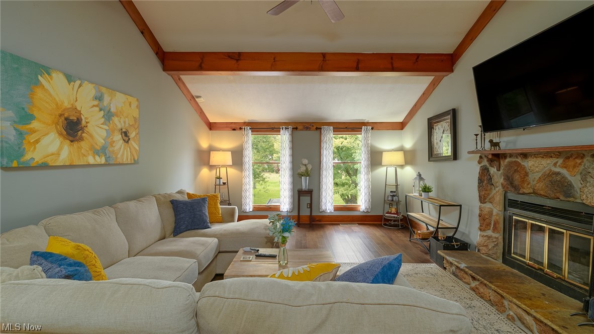 301 Perry Drive Northwest Canton, OH 44708 - Photo 21 of 34 Hardwood floored living room featuring a fireplace, ceiling fan, and vaulted ceiling with beams