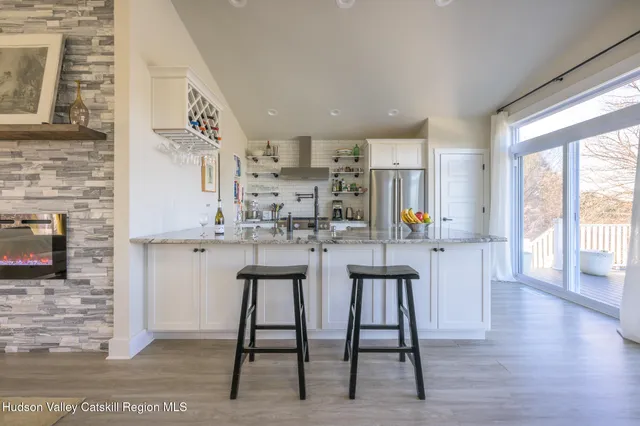 a kitchen with stainless steel appliances granite countertop a stove a sink and white cabinets with wooden floor