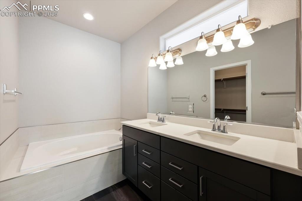 9962 Hidden Ranch Court Peyton, CO 80831 - Photo 31 of 48 a bathroom with a tub a double vanity sink and a mirror