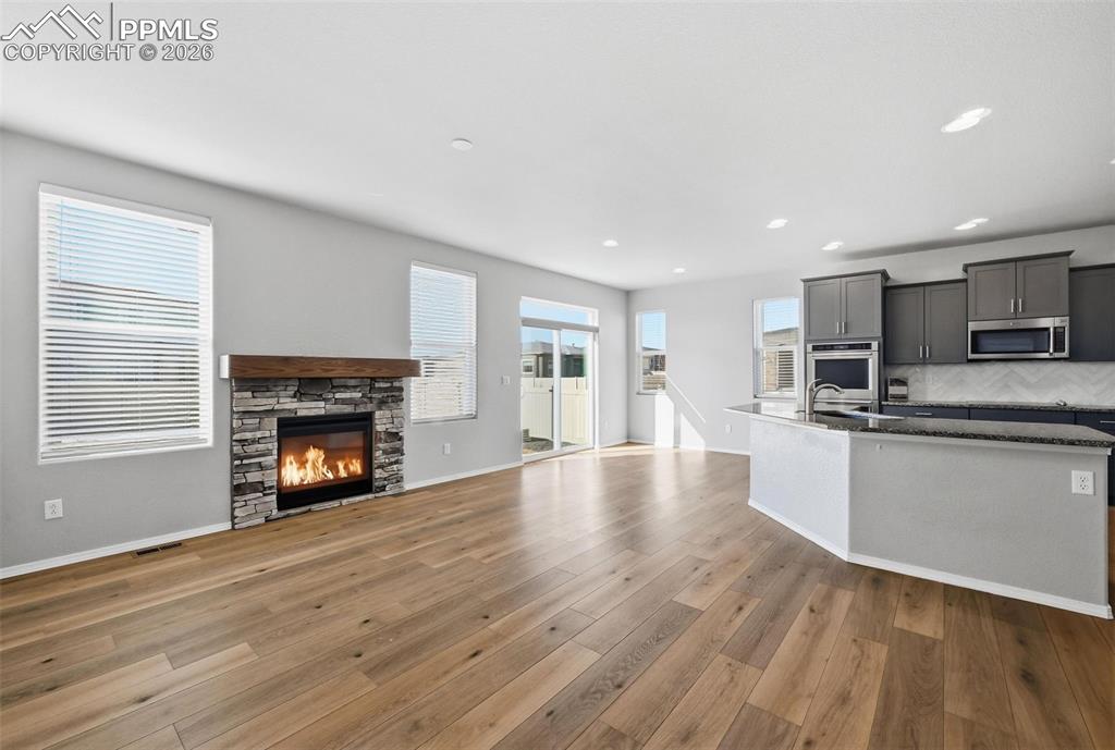 9962 Hidden Ranch Court Peyton, CO 80831 - Photo 5 of 48 a kitchen with stainless steel appliances a stove top oven a refrigerator and a fireplace with wooden floor