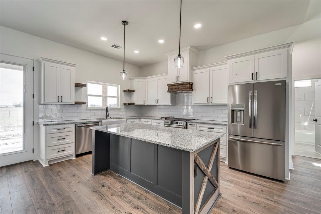 210 Wester Road Ferris, TX 75125 - Photo 22 of 25 a kitchen with kitchen island granite countertop a sink appliances a refrigerator and a counter top space