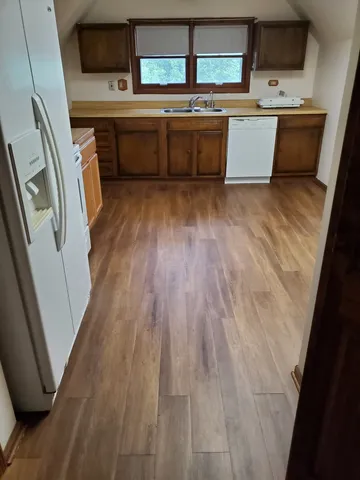 a view of a kitchen with wooden floor and electronic appliances
