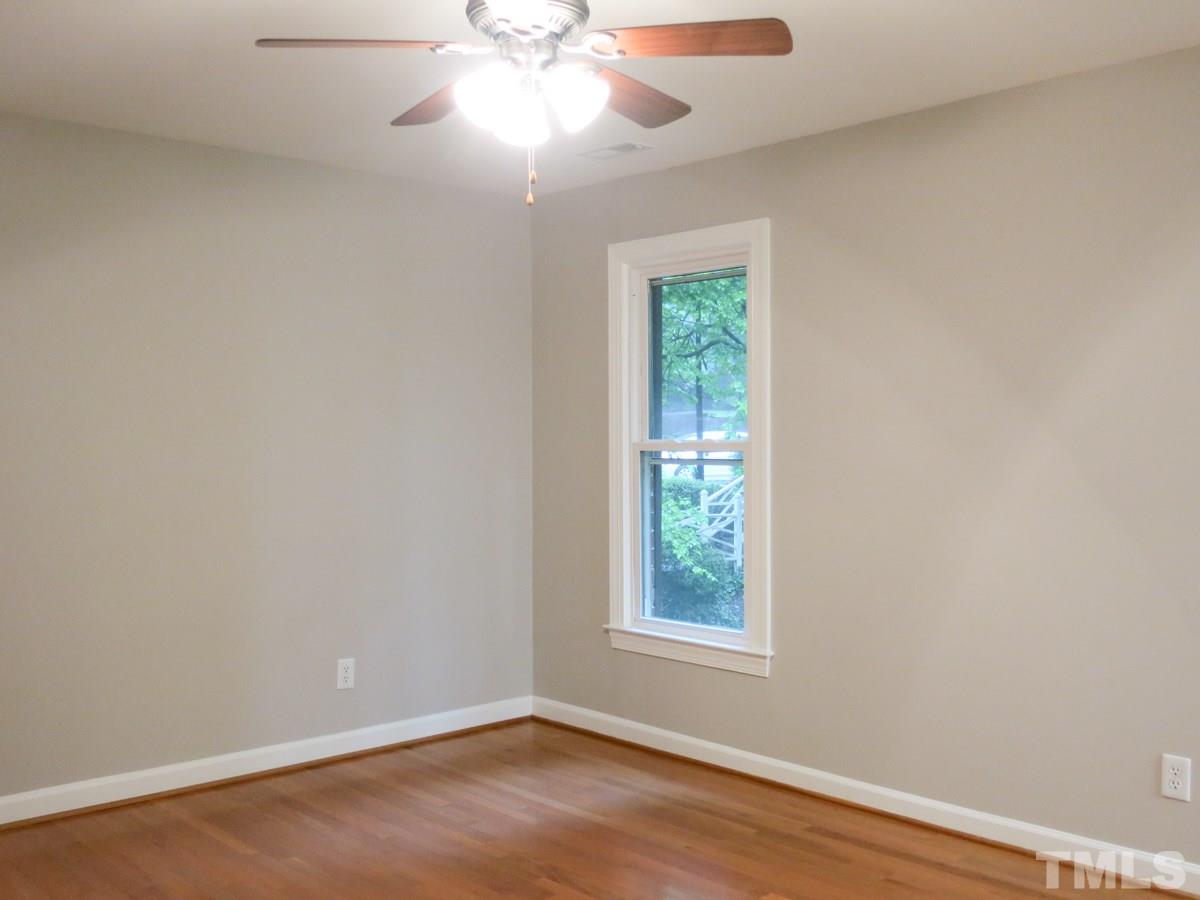 6820 Gloucester Road Raleigh, NC 27612 - Photo 14 of 25 an empty room with wooden floor chandelier fan and windows